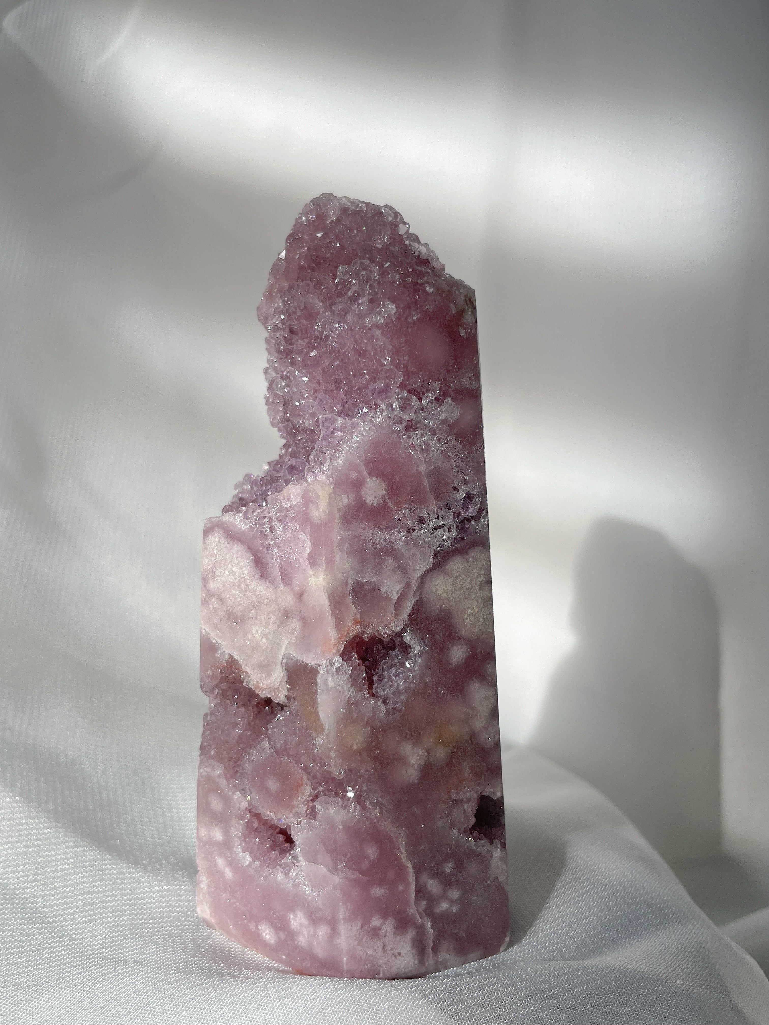 A beautiful pink amethyst crystal tower with a textured surface, showcasing soft lavender and cream hues.