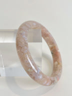 Beautiful flower agate bangle with soft pink hues, displayed on a clear stand.