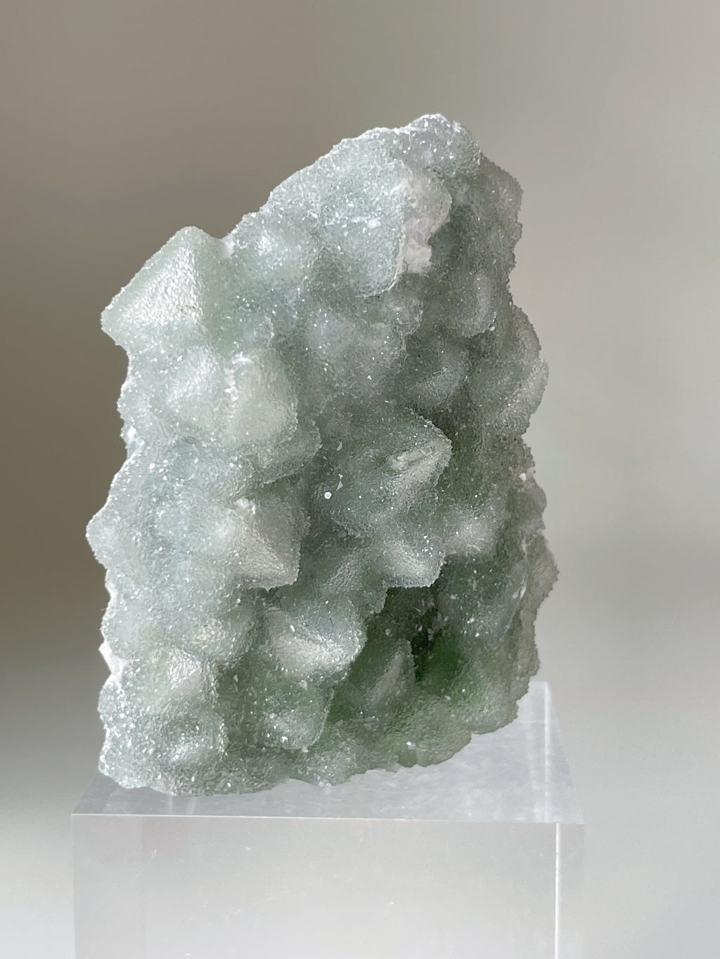 Beautiful green Fujian Sugar Fluorite crystal specimen with a textured surface, displayed on a clear stand.