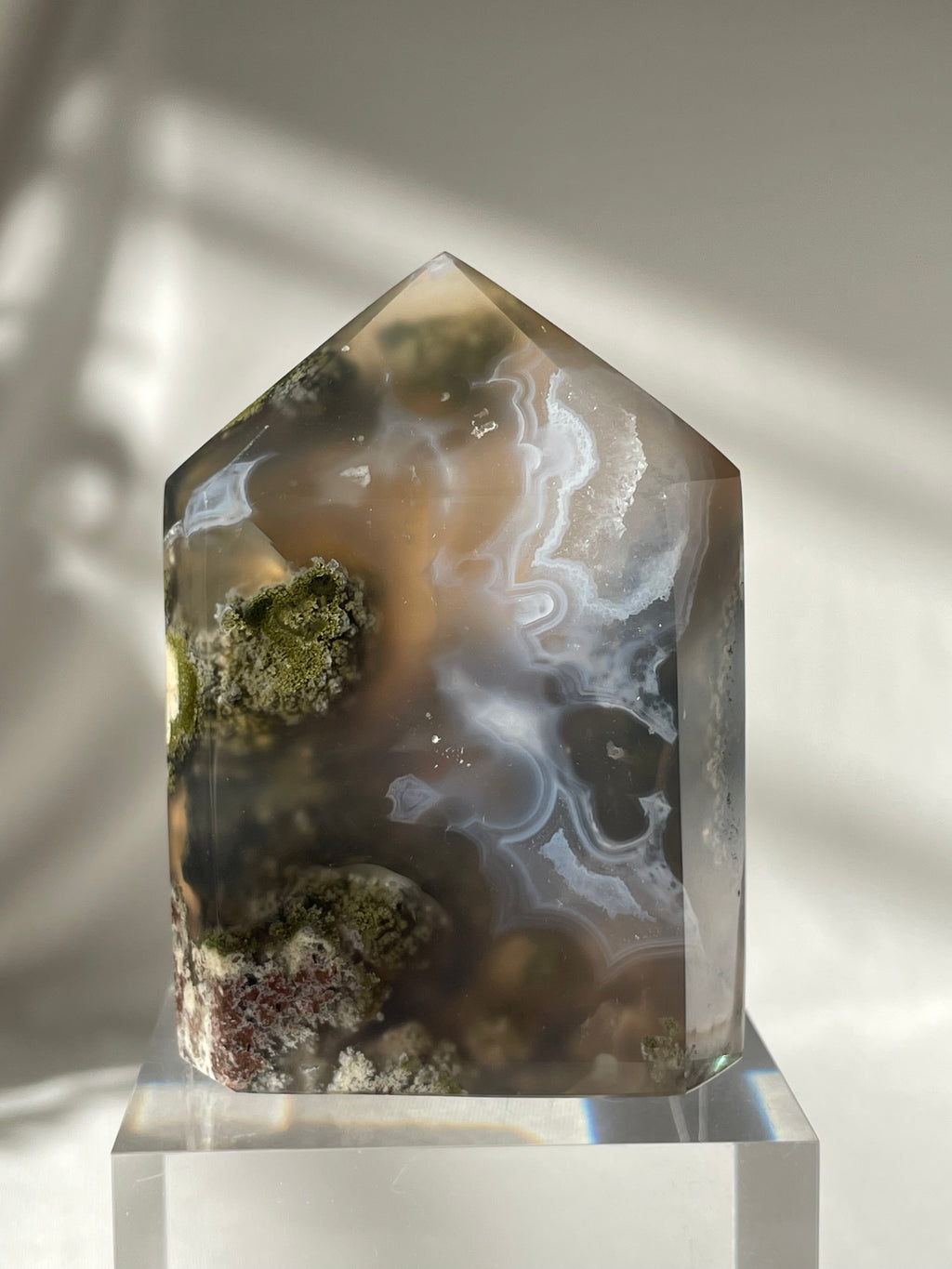 Scenic moss agate crystal tower with earthy tones and intricate patterns, displayed on a clear base.