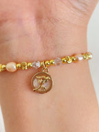 Delicate pink freshwater pearl bracelet with gold beads and a charm, elegantly worn on a wrist.