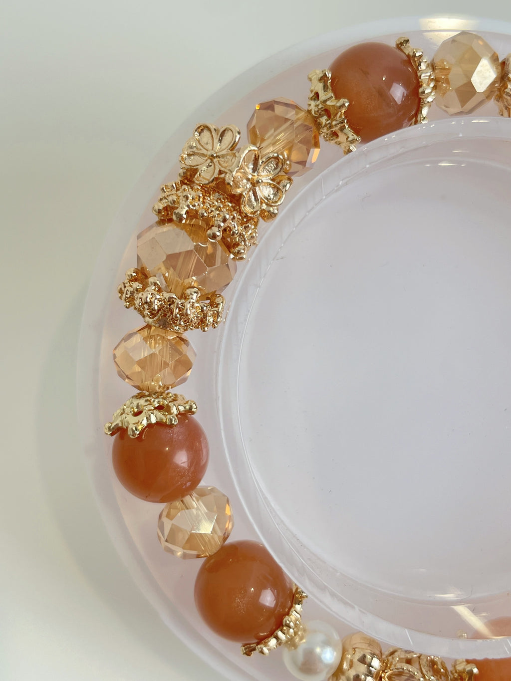 Elegant bracelet featuring warm-toned beads and gold accents, beautifully arranged on a clear display.