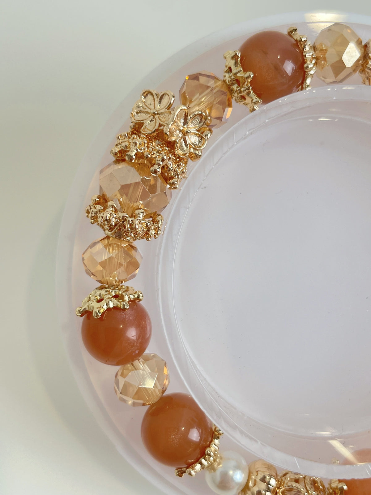 Elegant bracelet featuring warm-toned beads and gold accents, beautifully arranged on a clear display.