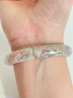Beautiful flower agate bangle showcasing soft pink and green hues, worn on a wrist.