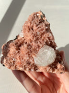 Beautiful pink Heulandite and Apophyllite crystal specimen held in hand, showcasing intricate mineral formations.