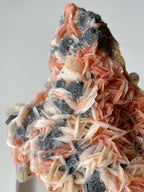Pink barite and cerussite crystals on galena, showcasing intricate formations and vibrant colors.