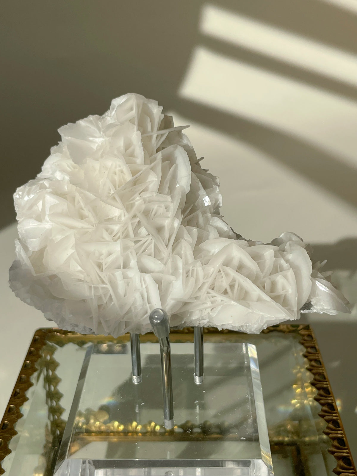 Beautiful petal bladed calcite specimen displayed on a clear stand, showcasing intricate crystal formations.