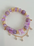 Lepidolite butterfly bracelet featuring purple beads, gold accents, and floral charms, showcasing a beautiful crystal design.