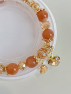 Sunstone bracelet featuring warm orange beads and gold accents, with a charming heart-shaped charm.