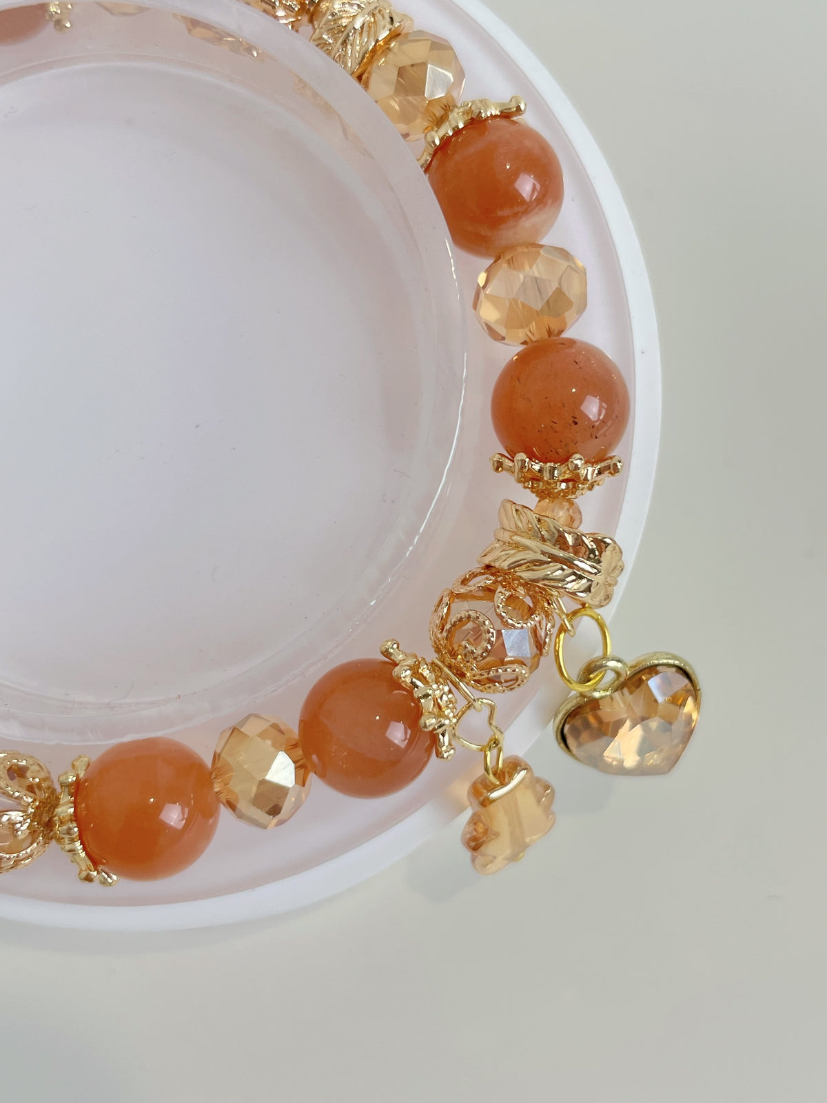 Sunstone bracelet featuring warm orange beads and gold accents, with a charming heart-shaped charm.