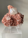 Beautiful pink Heulandite and Apophyllite crystal specimen displayed on a clear stand, showcasing intricate details.