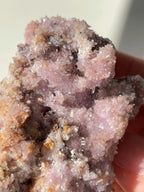 Beautiful purple creedite crystal specimen with sparkling facets, held in a hand, showcasing its natural beauty.