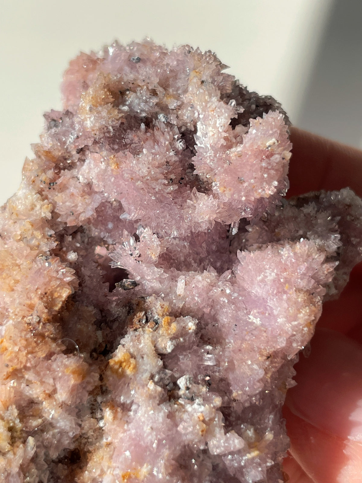 Beautiful purple creedite crystal specimen with sparkling facets, held in a hand, showcasing its natural beauty.