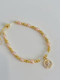 Delicate pink freshwater pearl bracelet with gold accents and a charm, perfect for elegant styling.