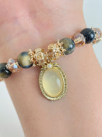 Elegant bracelet featuring blue tiger's eye beads and a gold pendant with floral accents.