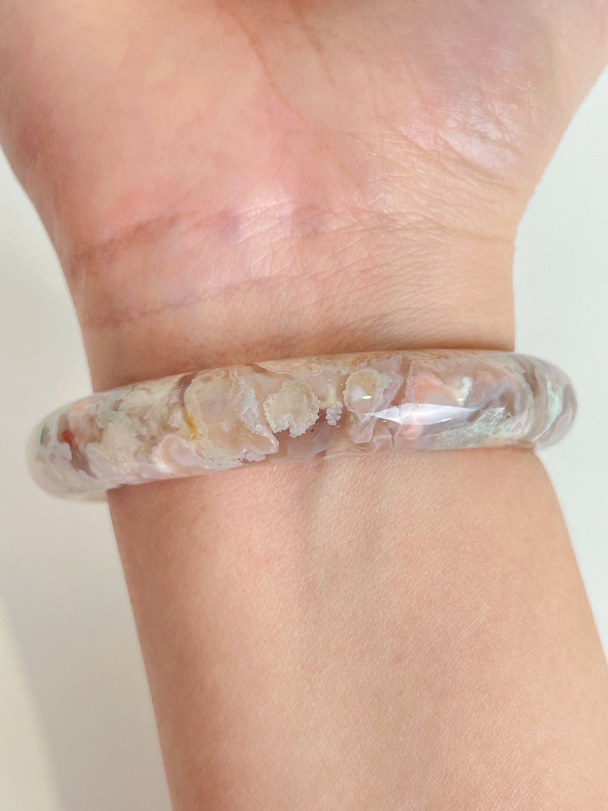 Flower agate bangle showcasing delicate floral patterns, worn on a wrist, highlighting its beautiful crystal design.