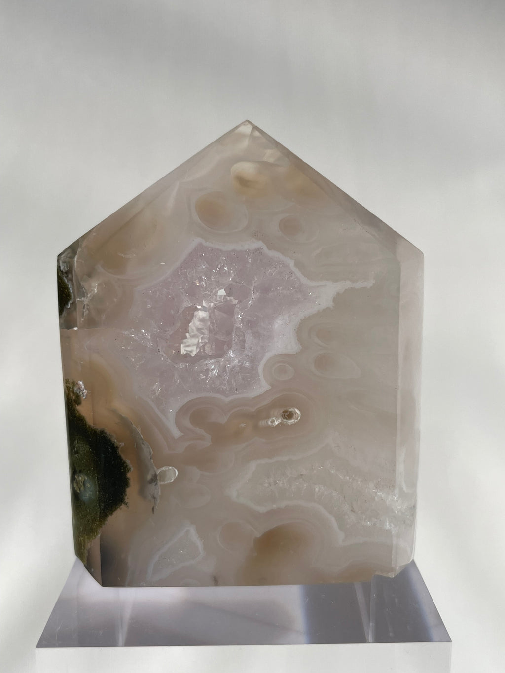 Scenic moss agate tower with soft pink and earthy tones, displayed on a clear stand, showcasing its unique patterns.