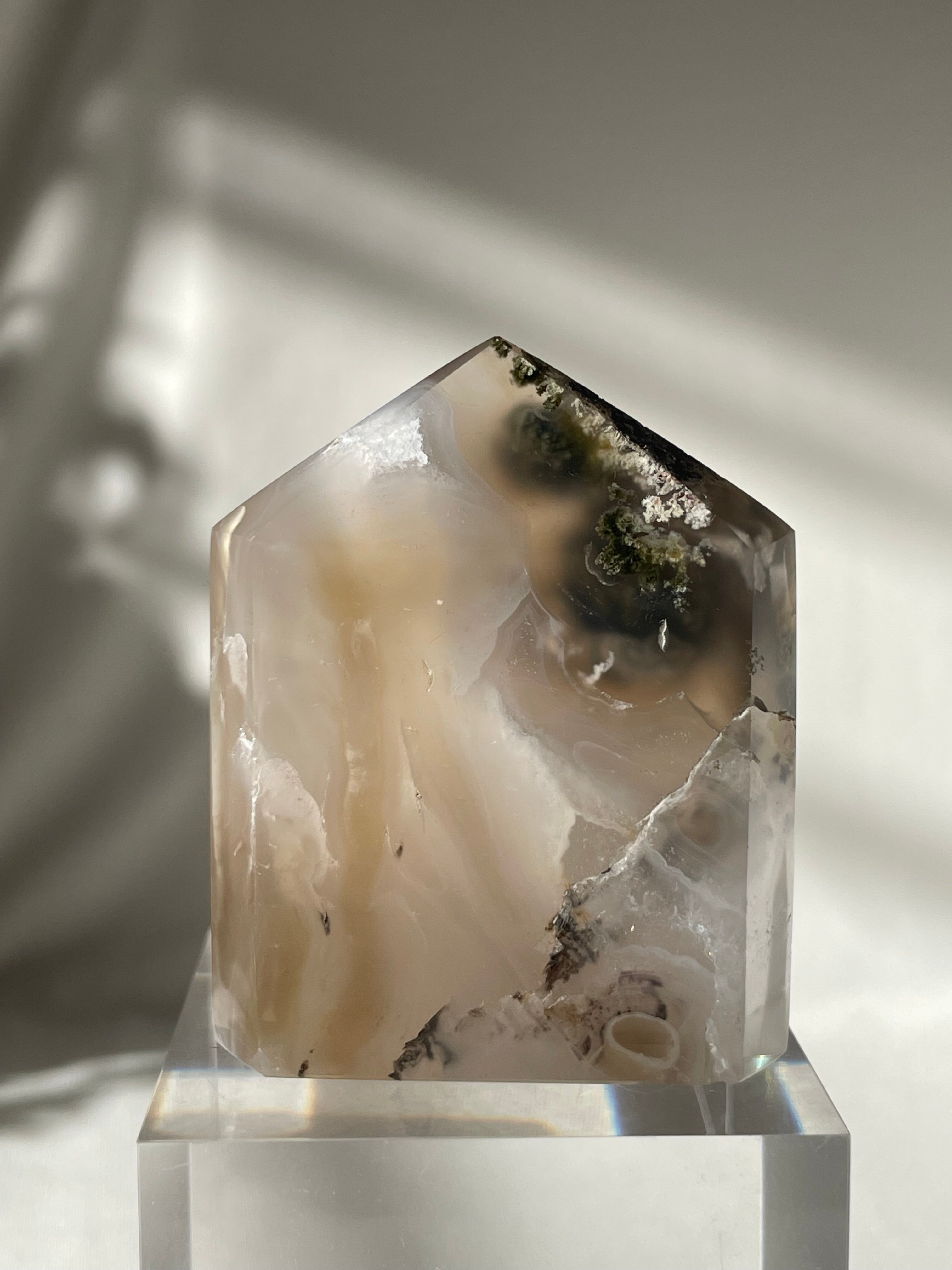 Scenic moss agate tower with soft earthy tones and natural patterns, resting on a clear base.