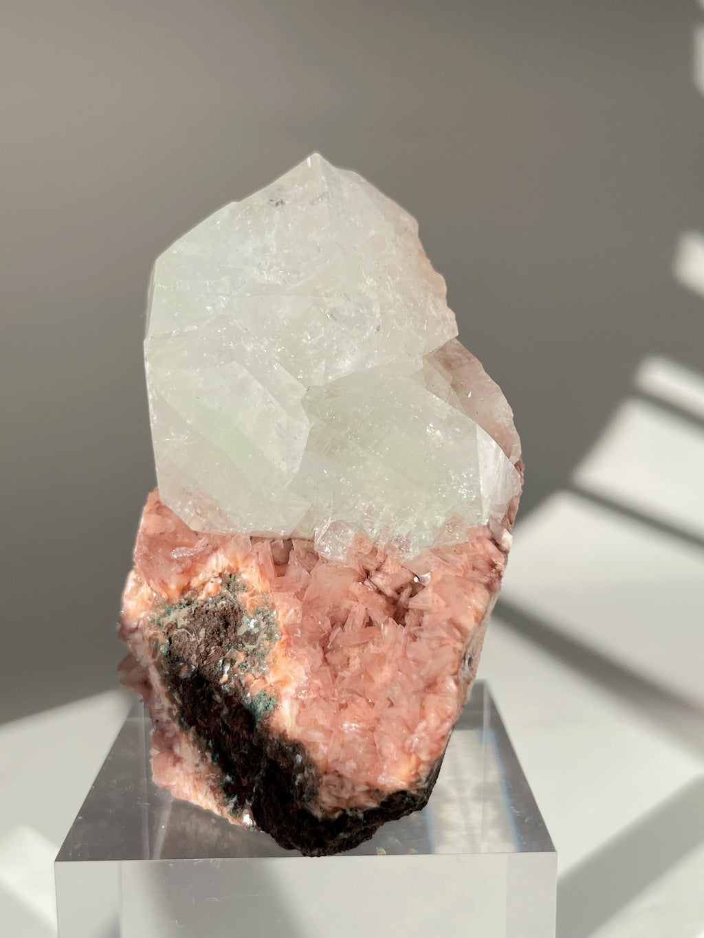 Beautiful pink Heulandite and Apophyllite crystal specimen displayed on a clear stand, showcasing its unique colors and