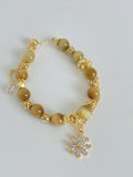 Gold Tiger's Eye bracelet featuring 8.3mm beads and a decorative flower charm, elegantly designed with golden accents.