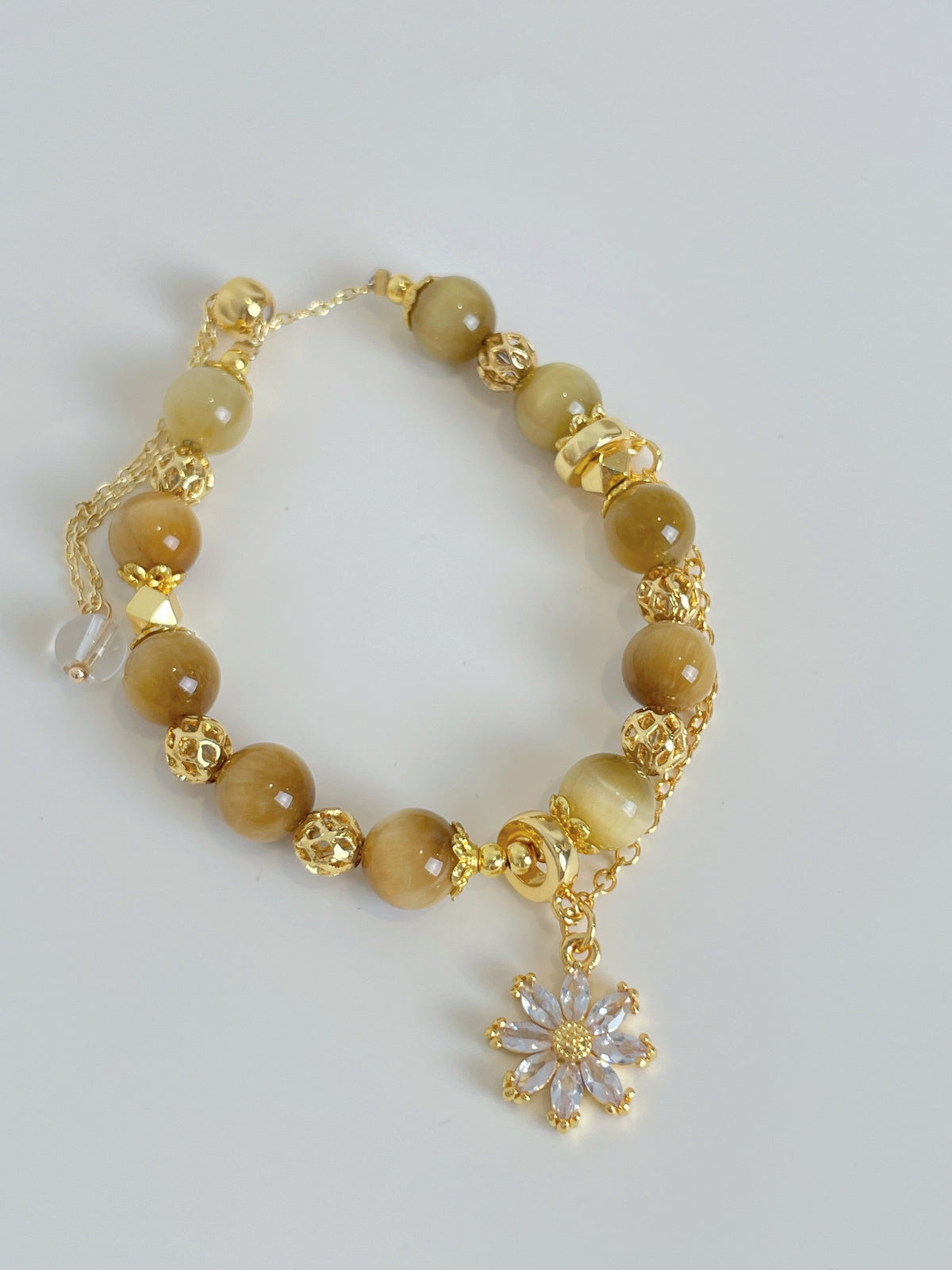 Gold Tiger's Eye bracelet featuring 8.3mm beads and a decorative flower charm, elegantly designed with golden accents.