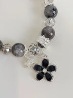 Beautiful quartz bracelet featuring a flower charm, accented with crystal and dark beads.