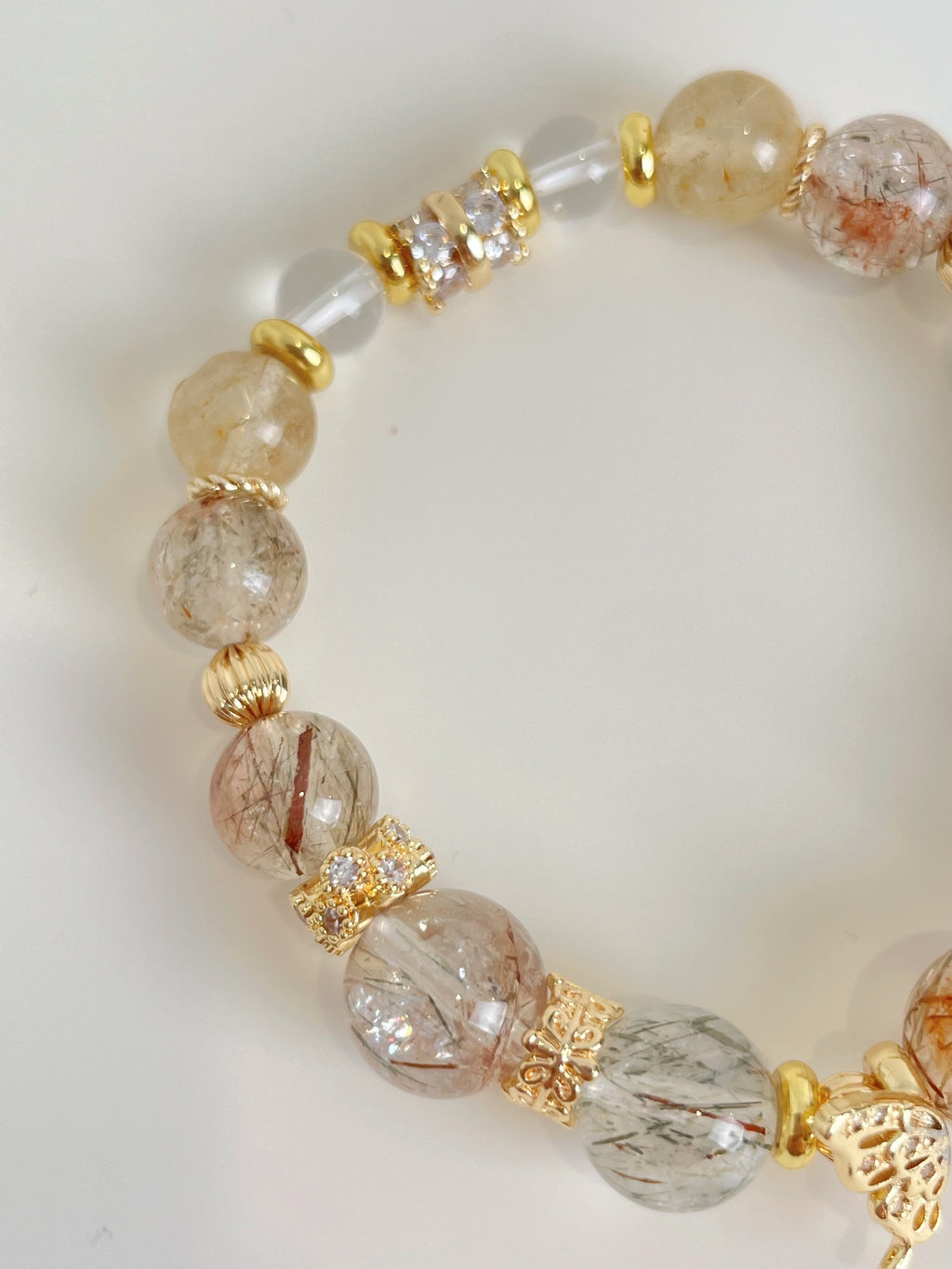 Rutile quartz bracelet featuring 9.5mm beads with golden accents and a mix of clear and smoky tones.