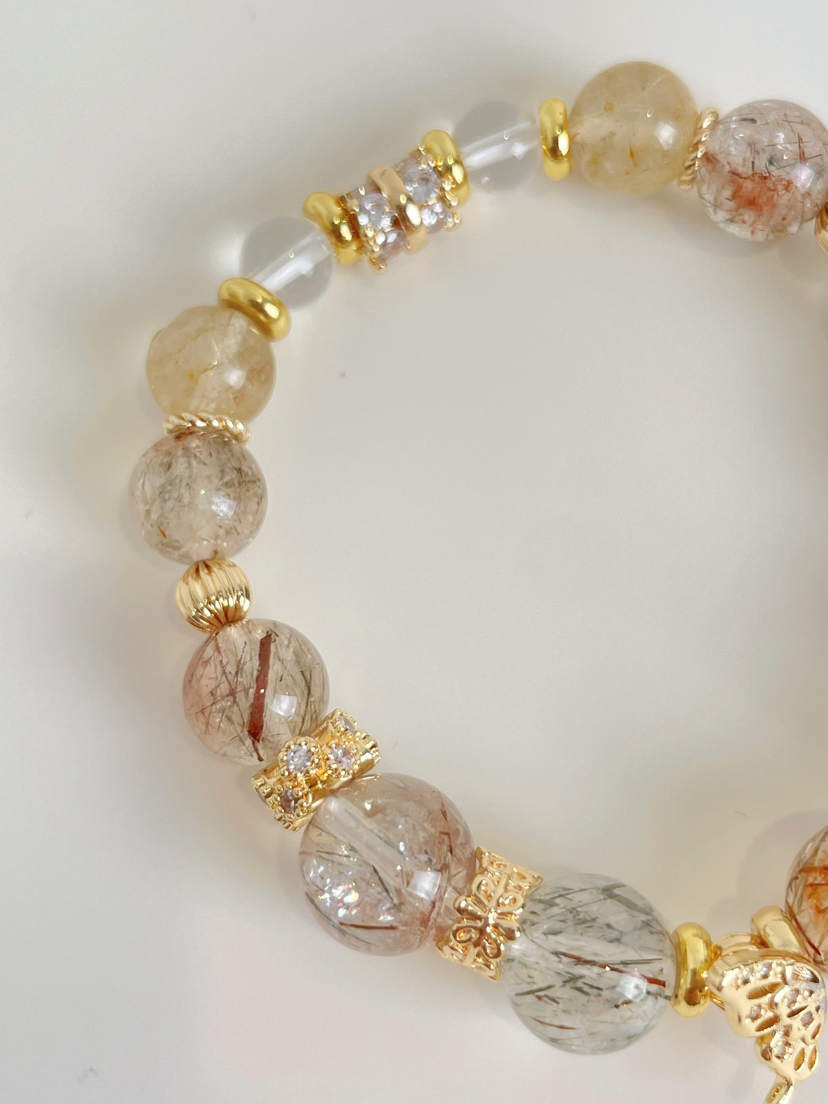 Rutile quartz bracelet featuring 9.5mm beads with golden accents and a mix of clear and smoky tones.