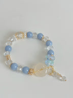 A delicate bracelet featuring light blue beads, clear crystals, and floral accents, showcasing a beautiful design.