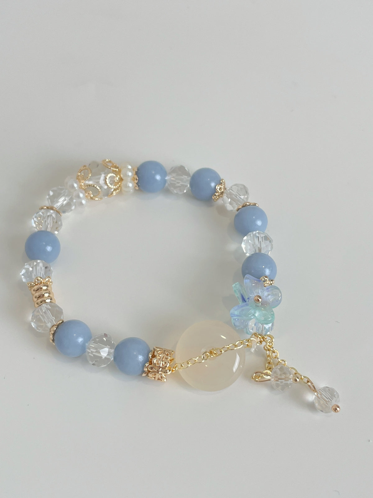 A delicate bracelet featuring light blue beads, clear crystals, and floral accents, showcasing a beautiful design.