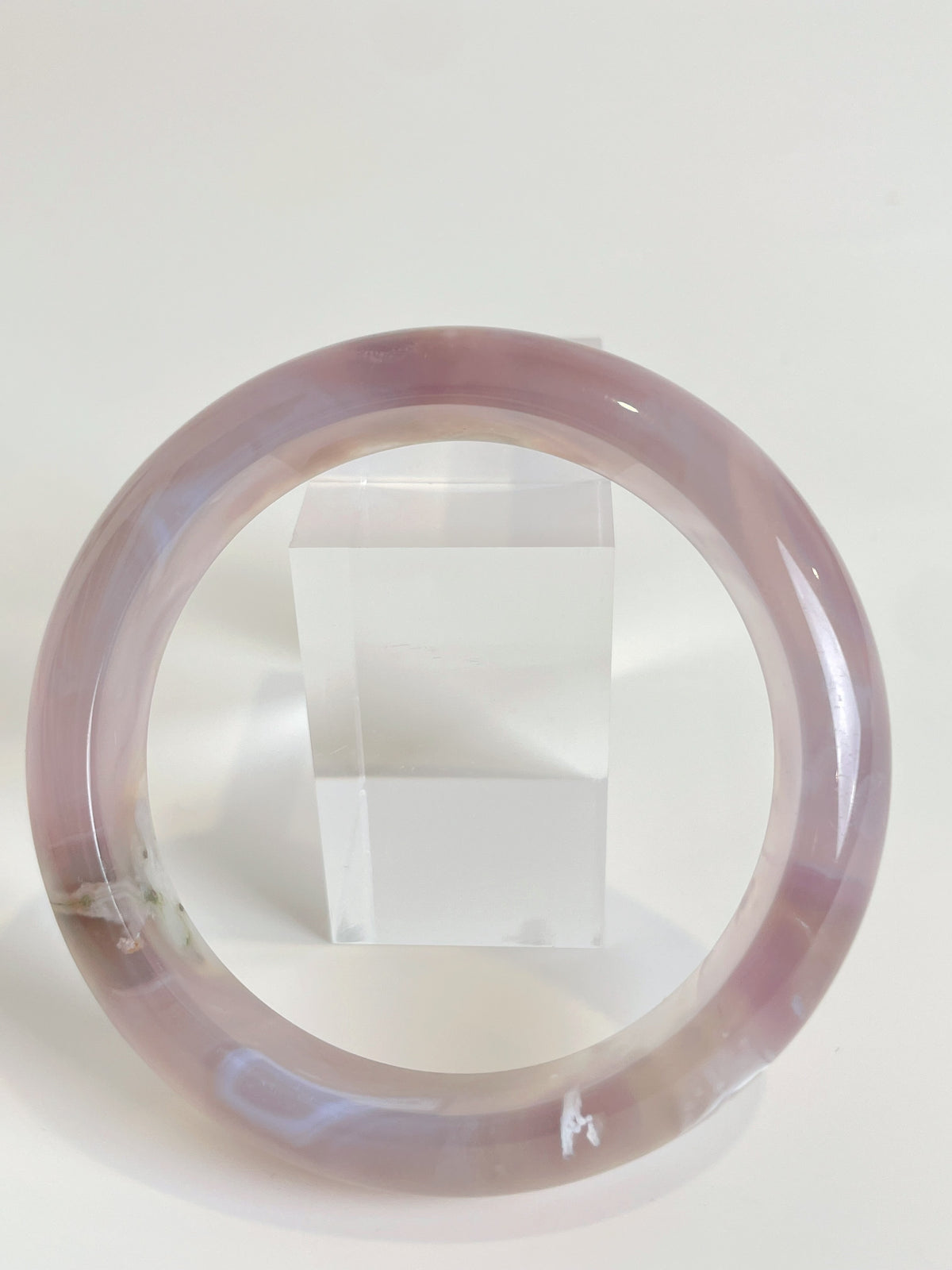 Beautiful flower agate bangle with soft pink hues, displayed beside a clear acrylic stand.