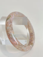 Beautiful flower agate bangle showcasing soft pink hues and floral patterns, displayed on a clear stand.