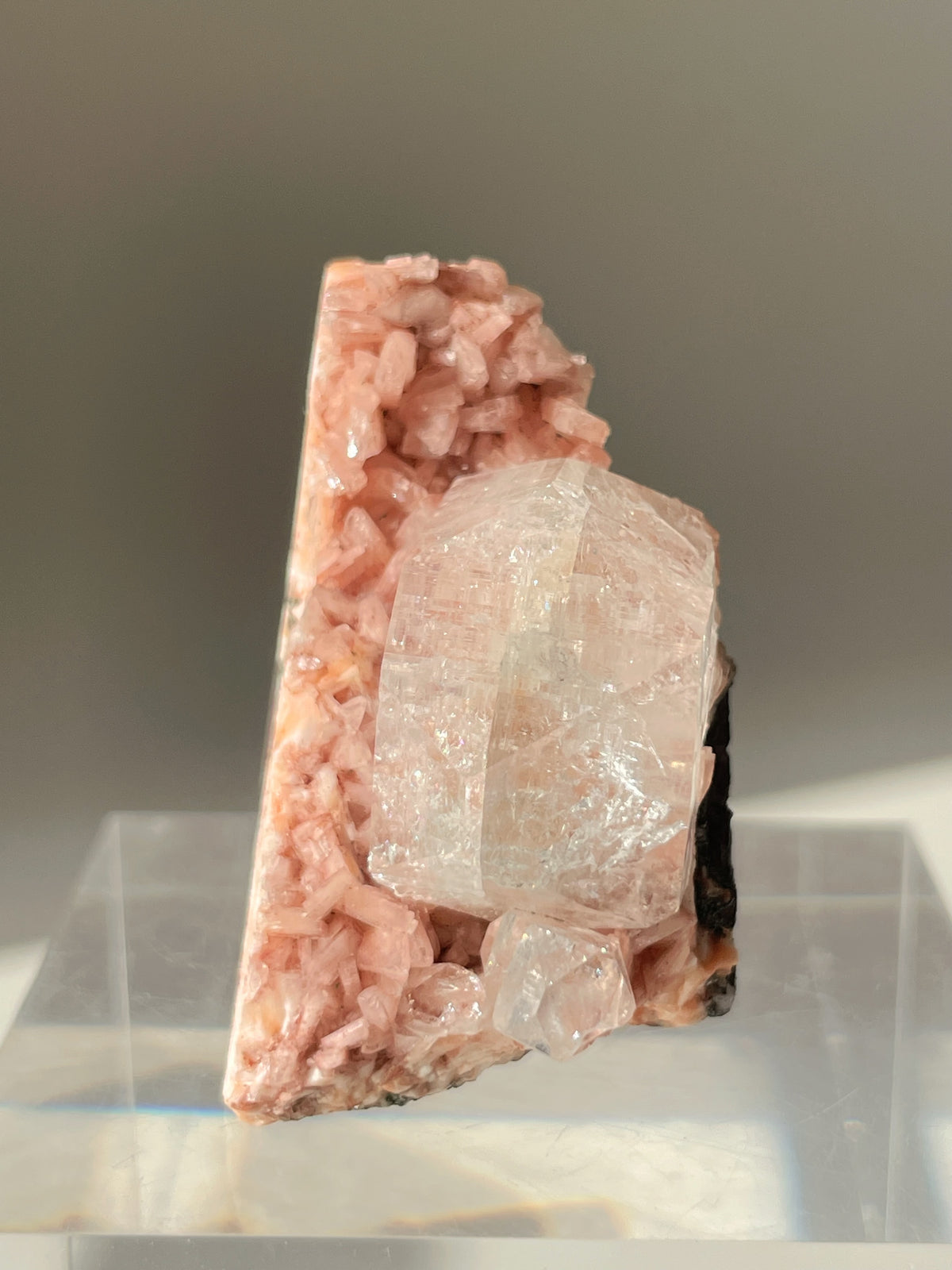 Beautiful pink Heulandite and Apophyllite crystal specimen displayed on a clear stand, showcasing its unique formations.
