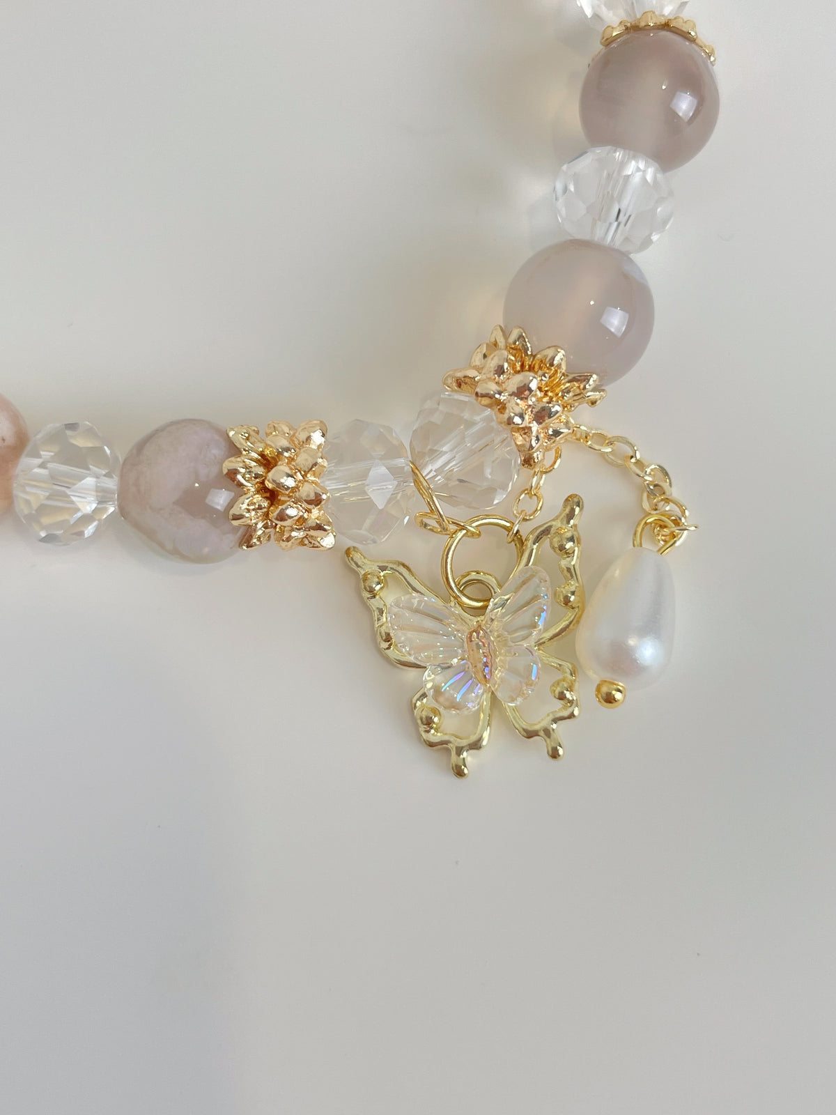 Beautiful flower agate bracelet featuring pink and clear crystals, adorned with a butterfly charm and pearl.