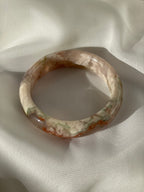 Beautiful flower agate bangle resting on soft fabric, showcasing its unique patterns and colors.