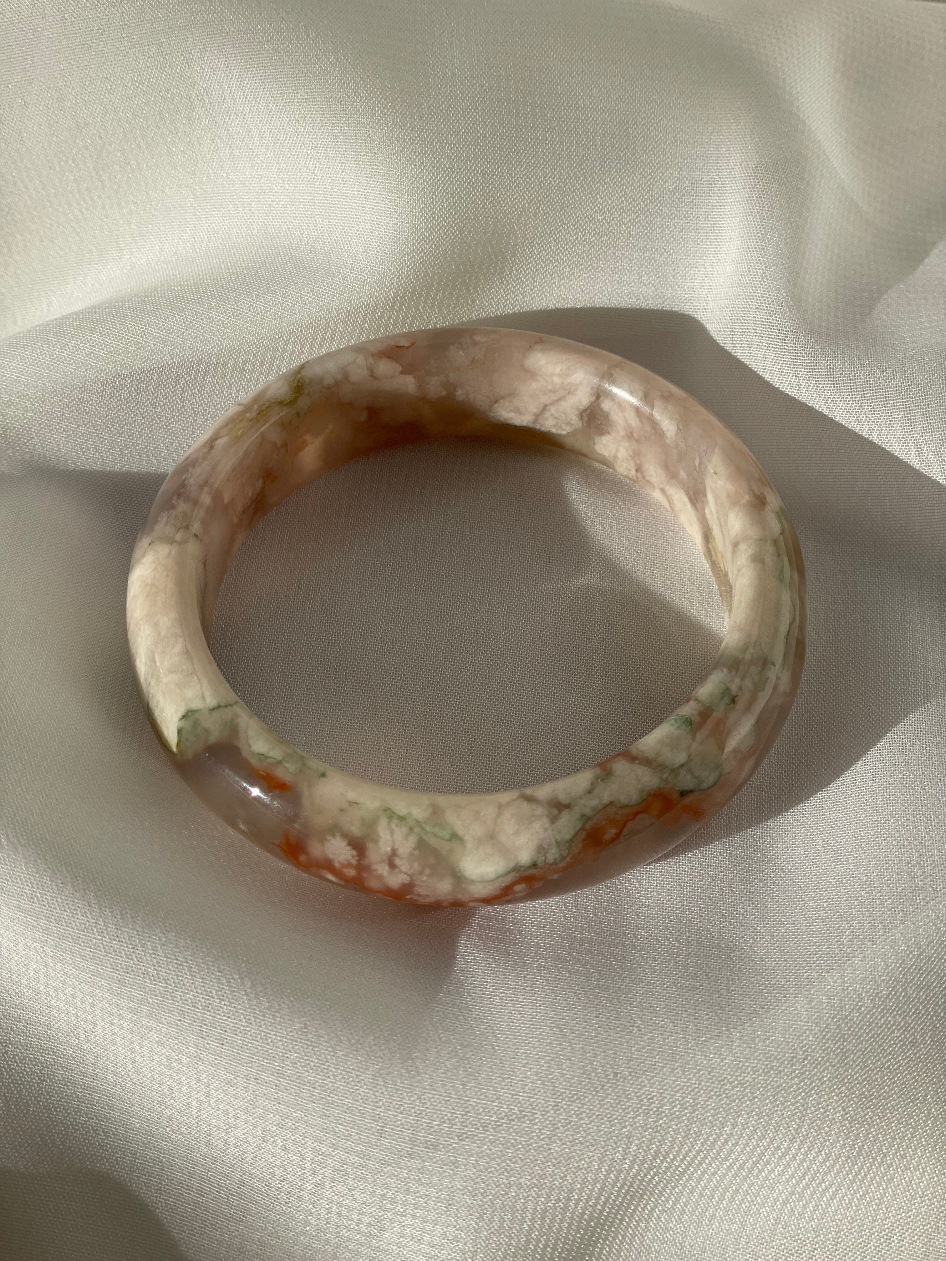 Beautiful flower agate bangle resting on soft fabric, showcasing its unique patterns and colors.