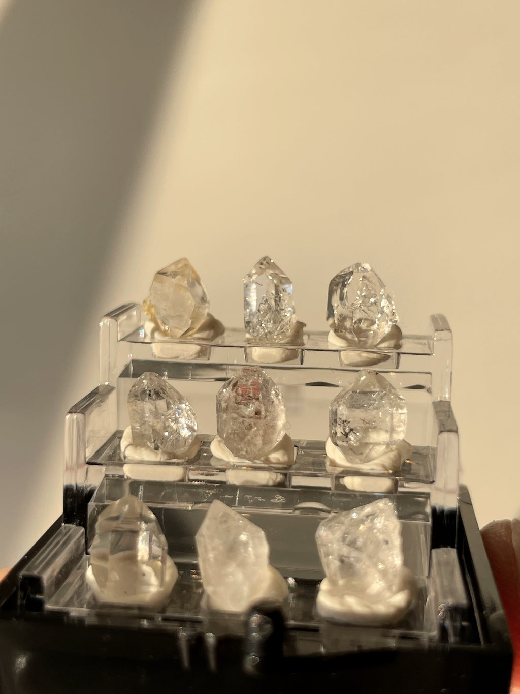 Nine sparkling Herkimer diamond crystal specimens displayed in a clear box, showcasing their natural beauty.