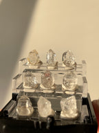 Nine sparkling Herkimer diamond crystal specimens displayed in a clear box, showcasing their natural beauty.