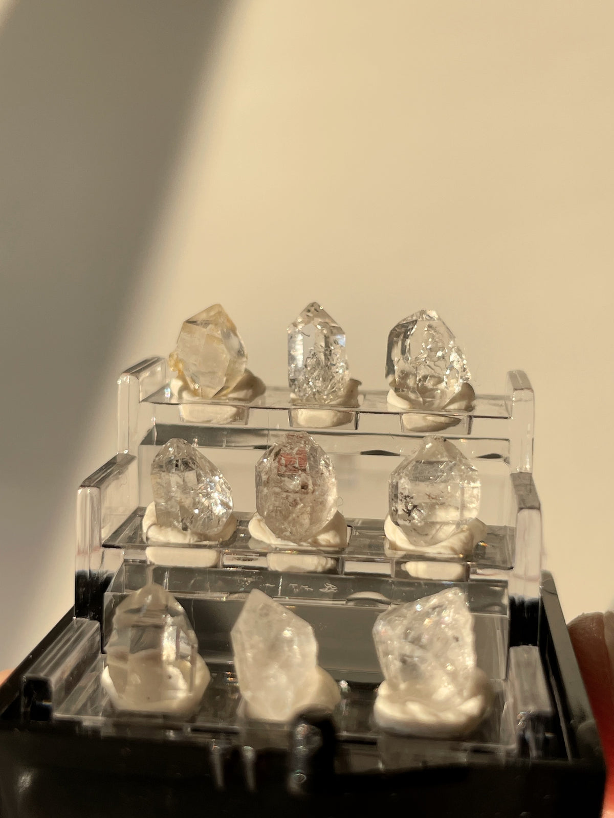 Nine sparkling Herkimer diamond crystal specimens displayed in a clear box, showcasing their natural beauty.