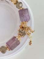 Elegant bracelet featuring pink amethyst cubes and faceted crystal accents, adorned with floral gold details.