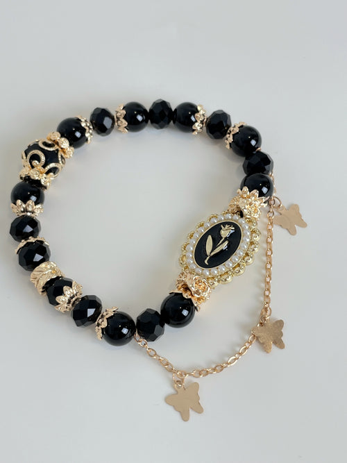 Elegant black obsidian bracelet featuring gold accents and butterfly charms, perfect for stylish accessorizing.