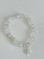 Elegant white quartz bracelet featuring faceted and smooth beads, accented with a silver snowflake charm.