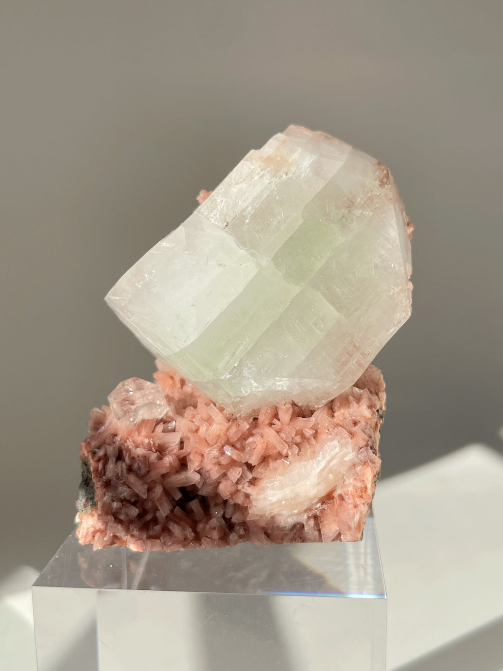 Beautiful pink Heulandite and Apophyllite crystal specimen on a clear display stand, showcasing its unique formations.