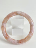 Beautiful flower agate bangle with soft pink hues, displayed against a clear stand.