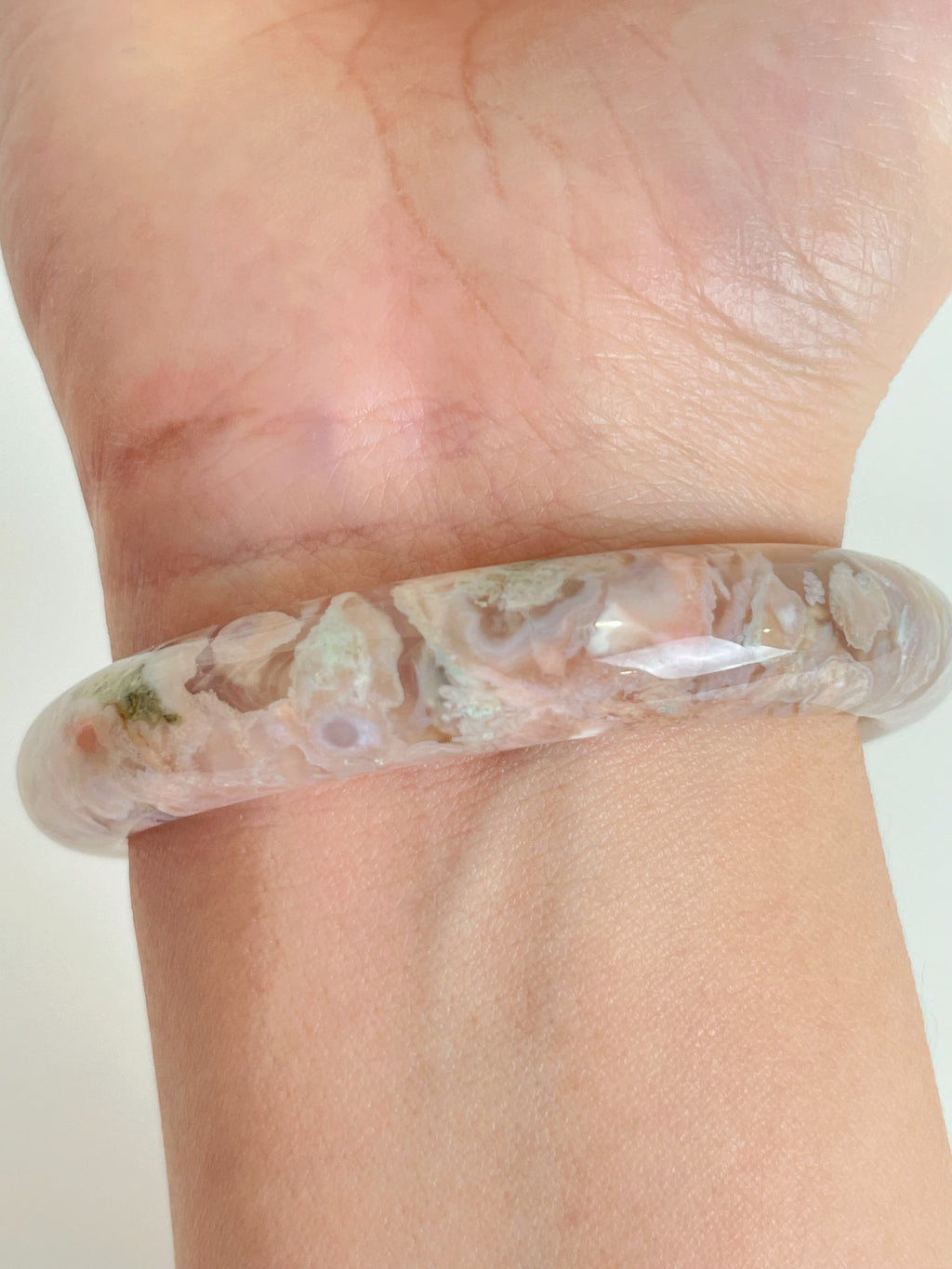 Beautiful flower agate bangle showcasing soft pink and earthy tones, worn on a wrist.