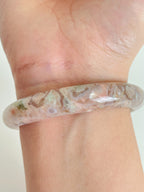 Beautiful flower agate bangle showcasing soft pink and earthy tones, worn on a wrist.