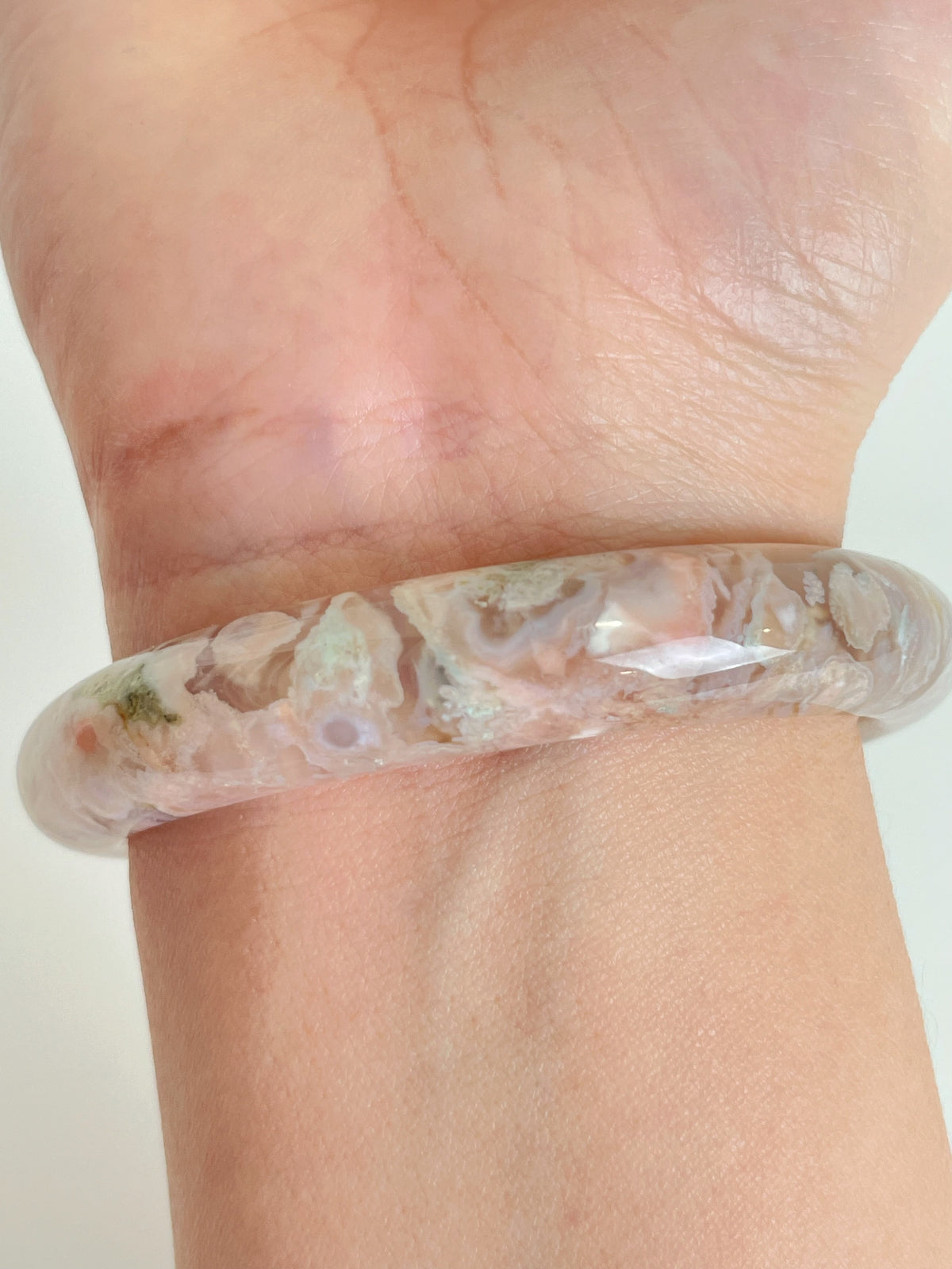 Beautiful flower agate bangle showcasing soft pink and earthy tones, worn on a wrist.