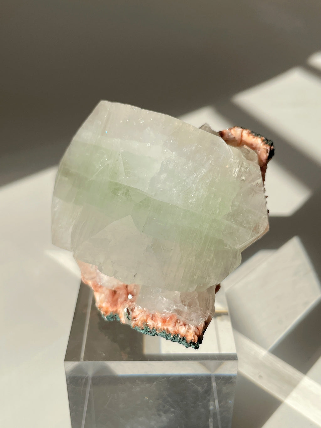 Beautiful pink Heulandite and Apophyllite crystal specimen displayed on a clear stand, showcasing its unique colors and