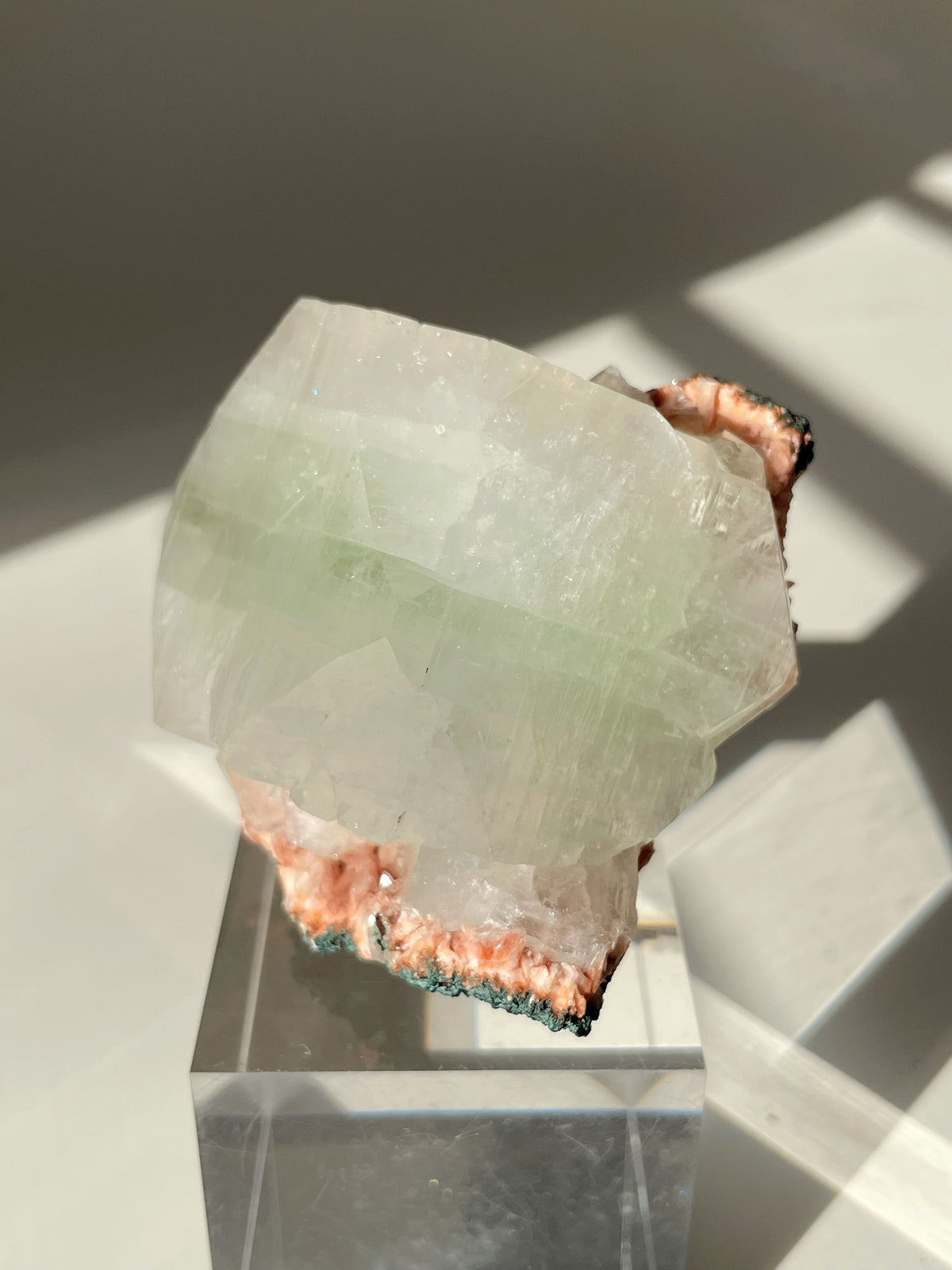 Beautiful pink Heulandite and Apophyllite crystal specimen displayed on a clear stand, showcasing its unique colors and