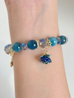 A beautiful blue apatite bracelet featuring 10mm beads, accented with sparkling crystals and a charming flower charm.